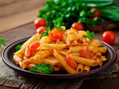 Penne pasta in tomato sauce with chicken and tomatoes  on a wooden table